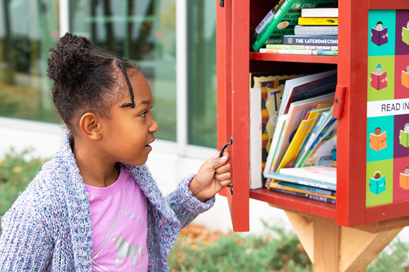 Young child opening the door to a Little Free Library